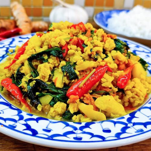 Chicken stir fried with turmeric, garlic, chillies and basil leaves on a dish.